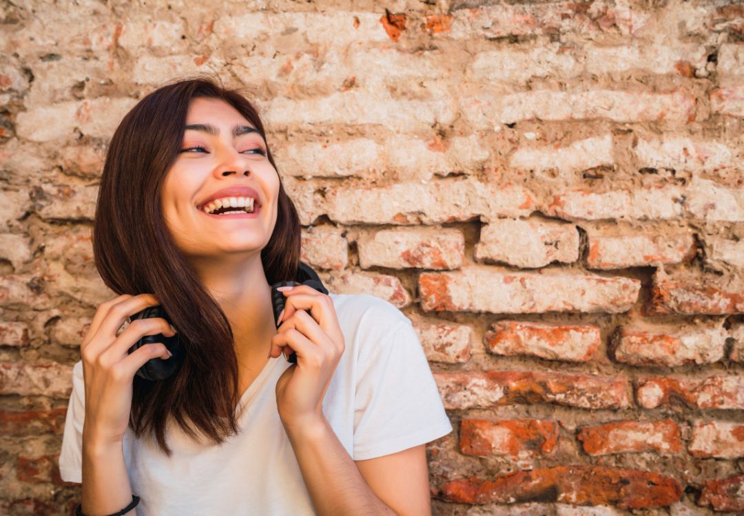 Joyful young female student laughing outdoors representing happiness in natural health programs